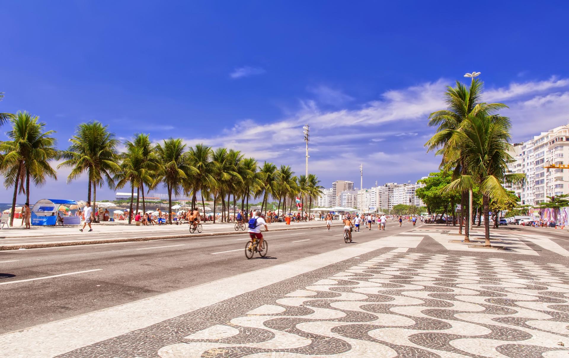 Copacabana Beach on a sunny day with a blue sky, view of the sea, and the city of Rio de Janeiro in the background