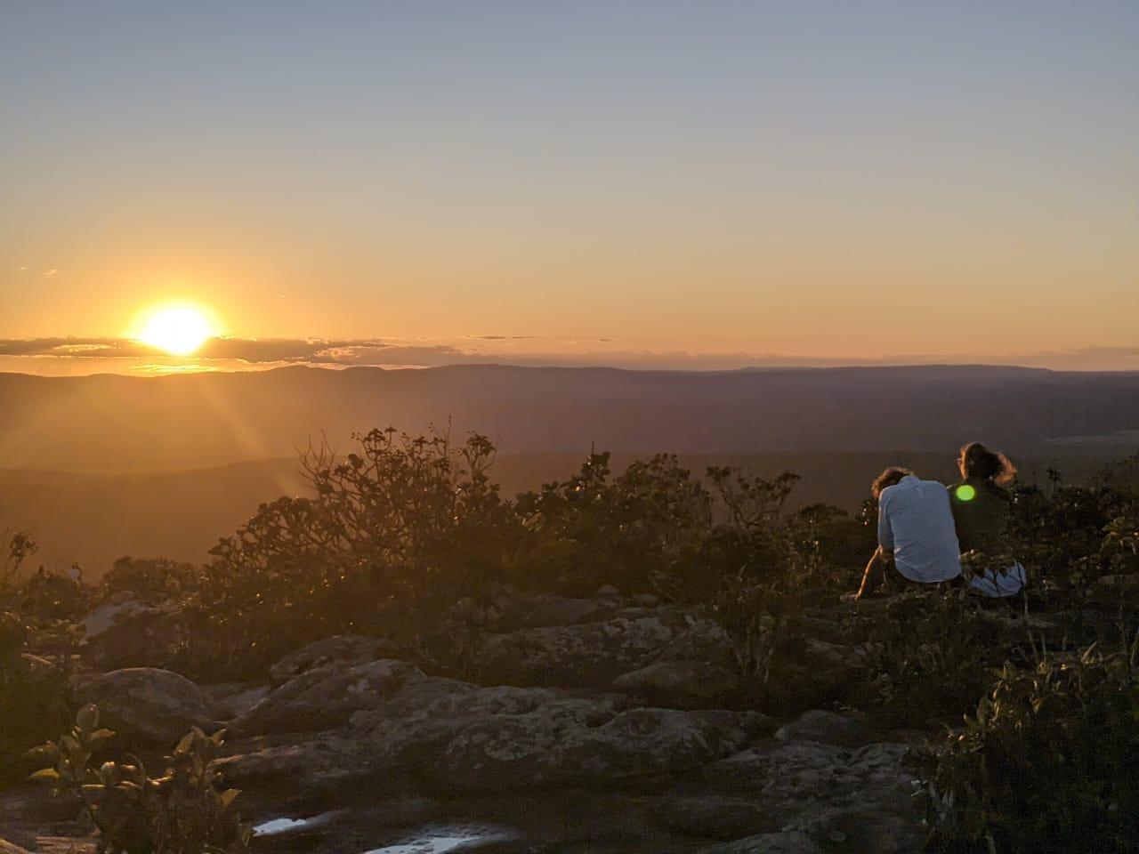 Two people sitting on Morro do Pai Inacio and watching the sunset